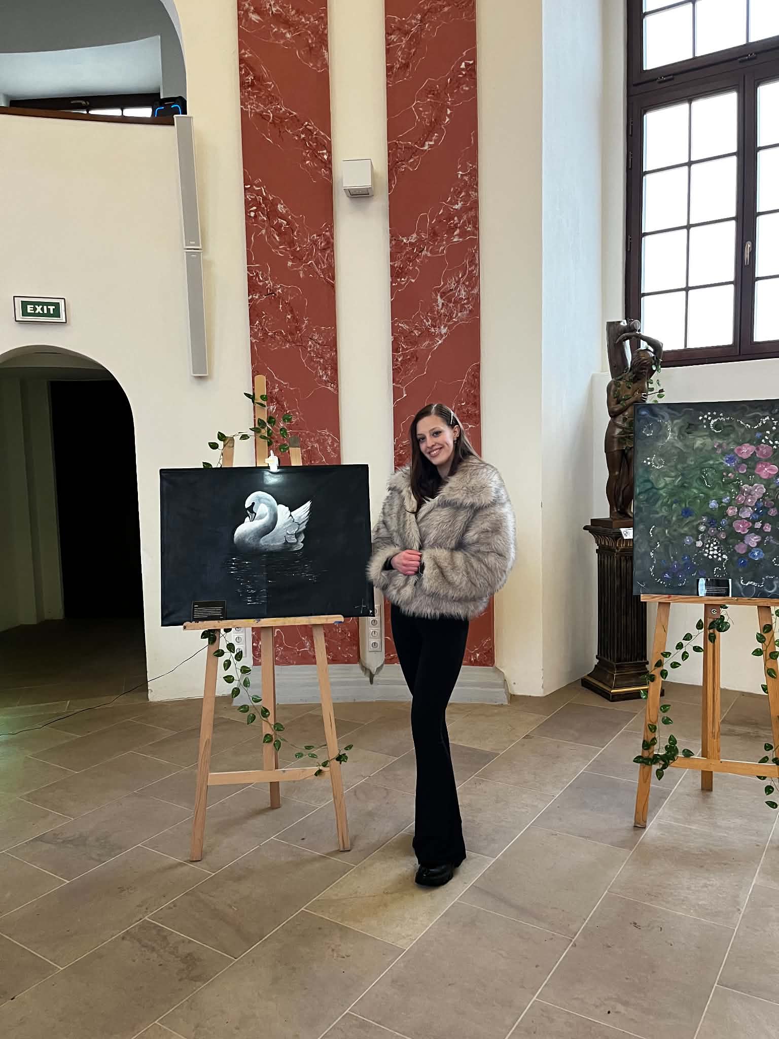 Katka Kocábová stojící mezi svými obrazy